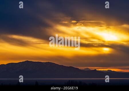 Le soleil couchant illumine les nuages au-dessus du parc national d'Antelope Island, vu de Layton, Utah, États-Unis. Banque D'Images