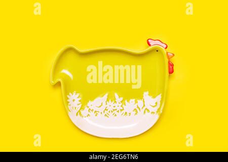 Cadre de pâques simple fond avec assiette de poule verte drôle sur couleur jaune vif, plat avec espace de copie Banque D'Images