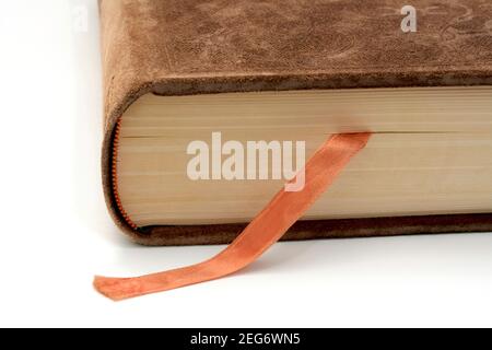 Livre relié en cuir marron avec un signet en ruban orange reposant sur une surface blanche et mettant en valeur son dos et sa couverture texturée Banque D'Images