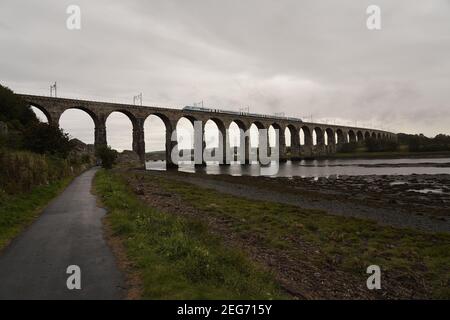 Le pont de la frontière royale qui longe la rivière Tweed avec un train moderne qui fait un zoom. Banque D'Images