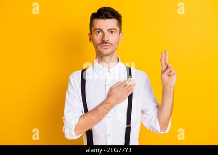 Photo portrait d'un homme calme et paisible qui serrons la main sur le cœur prêtre sérieux et confiant isolé sur fond jaune vif Banque D'Images