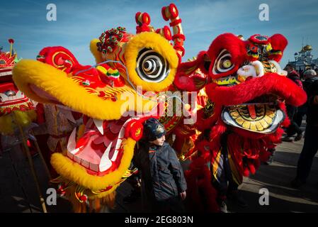 Célébrations du nouvel an de danse du dragon chinois à Eastbourne, Sussex, Royaume-Uni. Un jeune garçon à côté de dragons colorés jouant à l'événement traditionnel. Banque D'Images