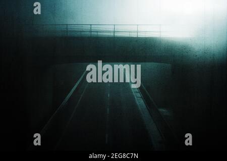 Un concept moody. Vue sur un pont traversant une route vide avec des feux de rue pendant une nuit brumeuse. Avec un grunge, artistique, montage Banque D'Images