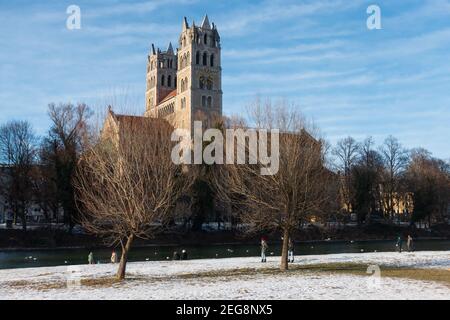 Munich, Allemagne - 13 février 2021 : vue sur l'église St Maximilian depuis le front de mer de l'Isar. Les gens qui marchent le long de l'esplanade en profitant du soleil Banque D'Images