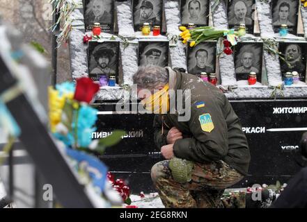 Kiev, Ukraine. 18 février 2021. Un homme s'agenouille à côté d'un mémorial à la mémoire de la centaine céleste, des militants qui ont été tués lors des manifestations anti-gouvernementales de 2014, à l'occasion du 7e anniversaire de l'Euro Maidan, à Kiev, en Ukraine, le 18 février 2021. Crédit : Serg Glovny/ZUMA Wire/Alay Live News Banque D'Images