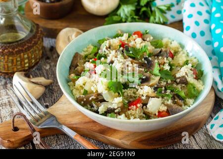 Concept végétalien de régime alimentaire. Salade végétalienne avec couscous et champignons sur une table en bois. Banque D'Images