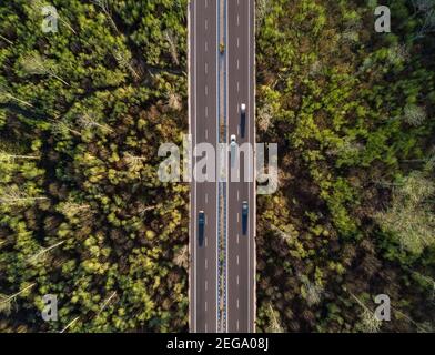 Vue d'en haut, vue aérienne stupéfiante de certaines voitures qui circulent le long d'une route flanquée d'une belle forêt. Sardaigne, Italie. Banque D'Images