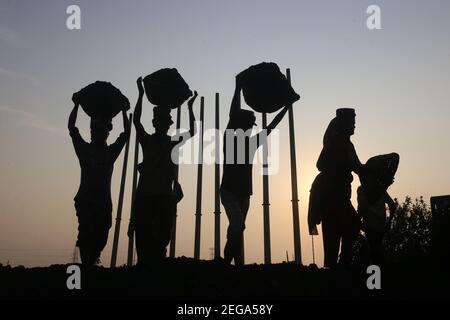 Dhaka, Bangladesh. 18 février 2021. Les travailleurs de jour ont défait du charbon sur leur tête d'un cargo près d'un entrepôt dans la banlieue de Dhaka. Crédit : MD Mehedi Hasan/ZUMA Wire/Alamy Live News Banque D'Images