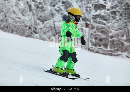 Ski enfant dans les montagnes. Tout-petit enfant actif avec casque de sécurité, lunettes et des poteaux. Course de ski pour les jeunes enfants. Sport d'hiver pour la famille. Le ski pour les enfants Banque D'Images