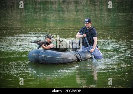 Entraînement des soldats. Forces spéciales en uniforme de camouflage pagayer un bateau militaire en caoutchouc. Bateau se déplaçant à travers la rivière, mission diversionnaire Banque D'Images