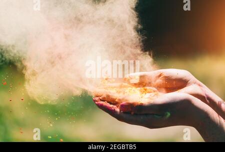 Poudre de Holi tenue dans la main de la femme et un nuage de poussière colorée. Célébration Holi. Banque D'Images