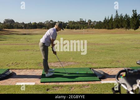 Femme caucasienne senior tenant un club de golf se préparant pour le tir sur le vert Banque D'Images