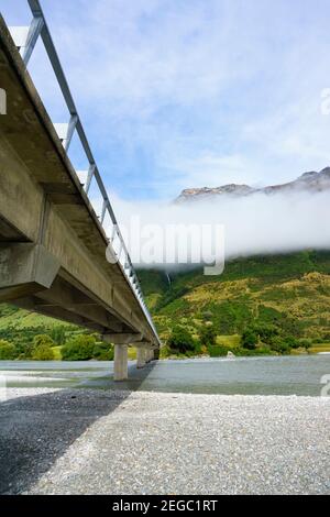 Pont et ombre à travers le lit de rivière pittoresque et rocailleux de la rivière Dart au pont te Araroa Trail à Otago, en Nouvelle-Zélande. Banque D'Images