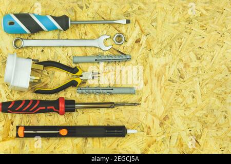 Les tournevis et les outils électriques sont répartis sur la table. Outils d'électricien sur une table en bois. Les tournevis, les cartouches, les fiches, les fils sont posés ou Banque D'Images