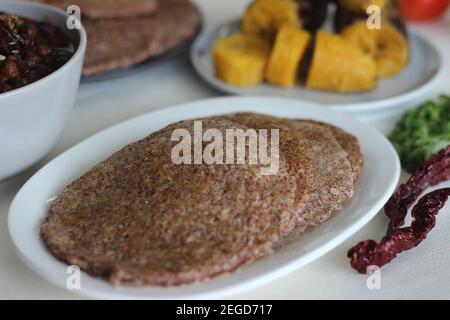 Crêpes faites maison au millet servi avec de la sauce aux pois chiches noirs et de la plantain à la vapeur. Expérimentez avec des minoteries à la maison. Photo sur fond blanc Banque D'Images