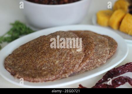 Crêpes faites maison au millet servi avec de la sauce aux pois chiches noirs et de la plantain à la vapeur. Expérimentez avec des minoteries à la maison. Photo sur fond blanc Banque D'Images