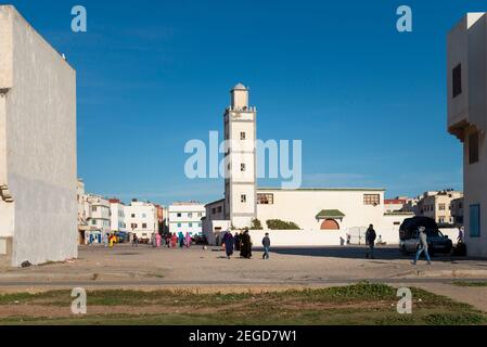 Essaouira, Maroc - 15 avril 2016 : scène de rue dans un quartier résidentiel de la ville d'Essaouira, avec des personnes marchant dans une rue et une mosqu Banque D'Images