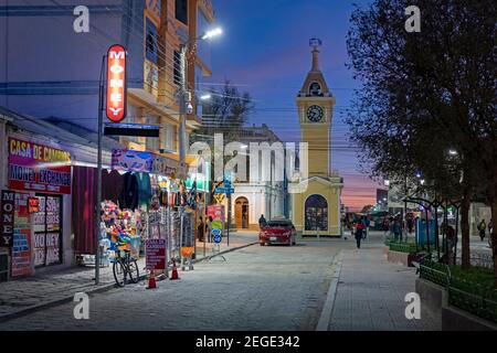 Boutiques dans la rue principale et tour d'horloge jaune dans la ville d'Uyuni après le coucher du soleil, province d'Antonio Quijarro, département de Potosí, Bolivie Banque D'Images