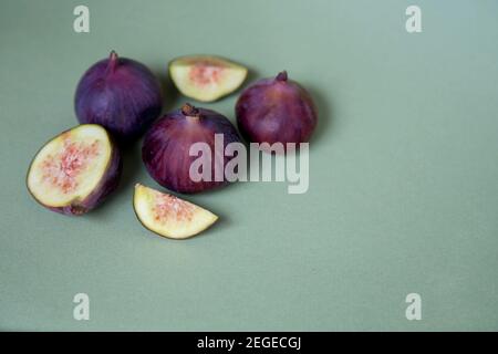 Figues entières et coupées mûres sur fond vert. Fruits de figue méditerranéens sains. La vie de notre vie minimaliste. Banque D'Images