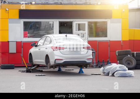 Changement rapide des roues, machine soulevée à l'extérieur près de la station-service Banque D'Images