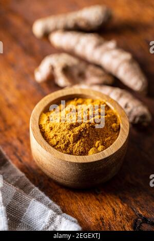 Poudre et racine de curcuma indienne. Épice curcuma. Curcuma moulu dans un bol sur une table en bois. Banque D'Images