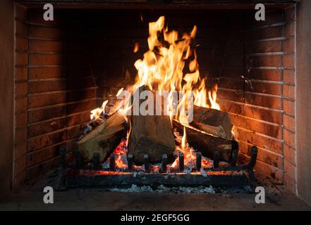 Cheminée, coin cheminée chaleureux. Feu brûlant, des bûches flamboyantes, arrière-plan de briques de feu. Détente à la maison vacances d'hiver temps de noël Banque D'Images