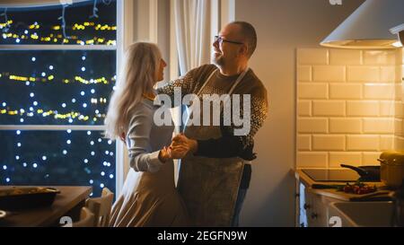 Beau couple Senior amoureux ont une soirée romantique, dansant dans la salle à manger, célébrant l'anniversaire. Portrait d'un mari et d'une femme âgés ont Banque D'Images