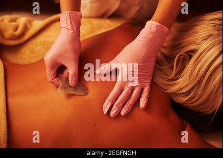 Femme blonde se relaxant sur une table de massage pendant un massage traditionnel chinois - Gua Sha. Traitement d'acupuncture Gua sha Banque D'Images