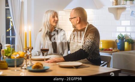 Joyeux couple Senior en amour ont une soirée romantique, la cuisine et le dîner dans la cuisine, célébrant l'anniversaire. Les personnes âgées ont une soirée romantique Banque D'Images
