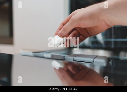 Homme mettant la tablette de détergent au lave-vaisselle. Banque D'Images