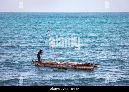 Silhouette de pêcheur sur bateau en bois. Océan Indien, horizon au-dessus de l'eau, bateau à voile traditionnel de dhow. Île de Zanzibar. Banque D'Images