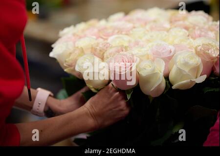Les mains du fleuriste tiennent un bouquet de roses blanches et roses Banque D'Images