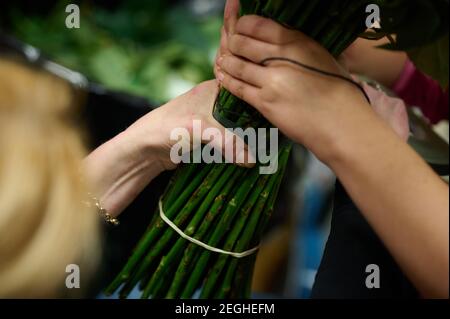 Procédé d'assemblage de bouquet, deux fleuristes tiennent le bouquet avec leurs mains Banque D'Images