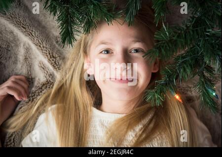 Adolescente/Tween couchée sur une couverture sous les branches de l'arbre de noël Banque D'Images