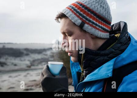 homme soufflant sur un café chaud prenant une pause en marchant En Angleterre Banque D'Images