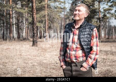 Portrait d'un bel homme d'âge moyen non rasé dans le parc. Homme adulte en chemise et gilet extérieur. Arrière-plan flou. Copier l'espace. Banque D'Images