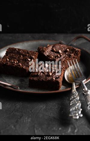 Cuisine maison confortable. Des brownies au chocolat délicieux avec des morceaux de srawberries secs et des gouttes de chocolat sur fond sombre Banque D'Images