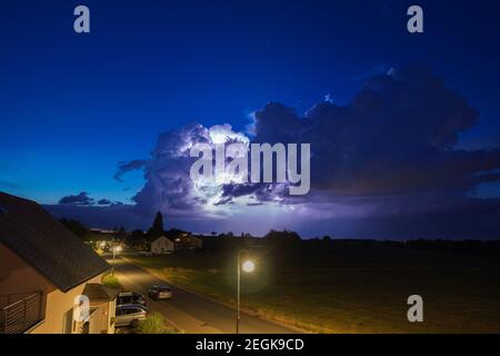 Flashs dans les nuages d'orage sur la prairie dans le village allemand d'ailleurs une rue la nuit Banque D'Images