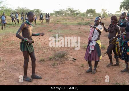 Femmes de la tribu Banna avec le jeune homme participant à la cérémonie de saut à la taureau. La cérémonie de saut à la taureau est un rite de passage masculin où un Banque D'Images