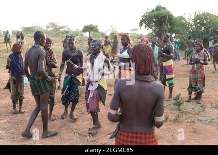 Femmes de la tribu Banna avec le jeune homme participant à la cérémonie de saut à la taureau. La cérémonie de saut à la taureau est un rite de passage masculin où un Banque D'Images