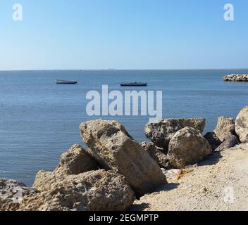 Deux canoës flottent sur la mer des Caraïbes sous le bleu ciel avec rochers au premier plan Banque D'Images
