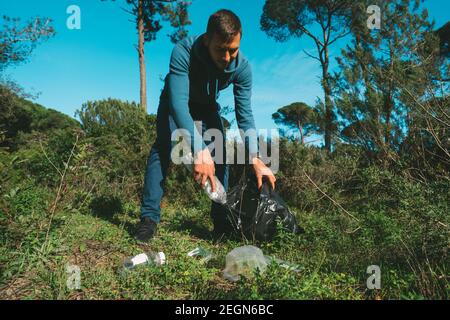 Je ramassant une poubelle en plastique dans la forêt. Nettoyage de la nature. Déchets et ordures à l'extérieur. Nature verte et propre Banque D'Images