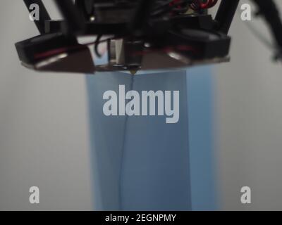 Gros plan de la pointe de l'imprimante 3D lorsqu'elle extrude des couches de plastique, filament en pla bleu translucide extrudé par une imprimante delta Banque D'Images