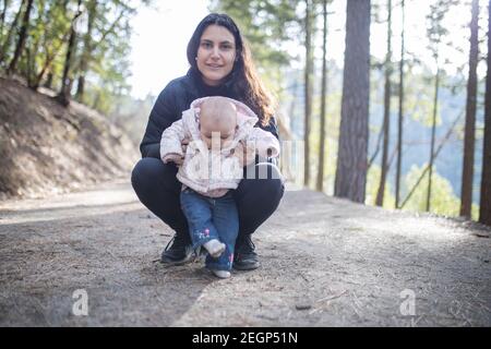 Bonne femme tenant son adorable bébé dans la forêt Banque D'Images