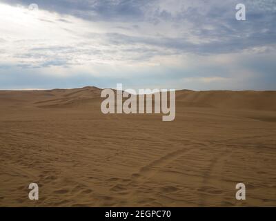 Dunes de sable doré dans le désert de Huacachina au Pérou, buggies et personnes au loin Banque D'Images