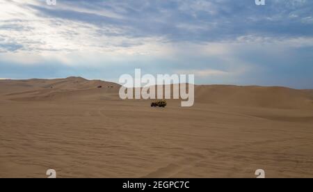 Buggy jaune au désert de l'ICA au pérou, dunes de sable sous le ciel bleu Banque D'Images