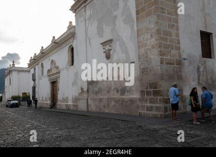 Guatemala, Antigua - 26 mai 2019 - touristes marchant à côté du bâtiment avec des détails sculptés sur les murs blancs, rouille et taches sur la peinture blanche Banque D'Images