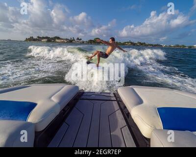 Un homme sportif tombe de la planche tout en wakesufing à la mer, à l'arrière du bateau dans le cadre Banque D'Images