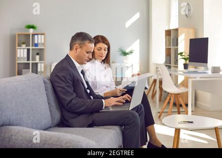 Des professionnels ciblés utilisant un ordinateur portable, travaillant sur un projet, entrant des données, réalisant des tâches administratives Banque D'Images