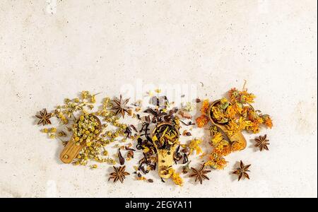 Variété de feuilles de tisanes sèches éparpillées sur des cuillères en bois. Banque D'Images